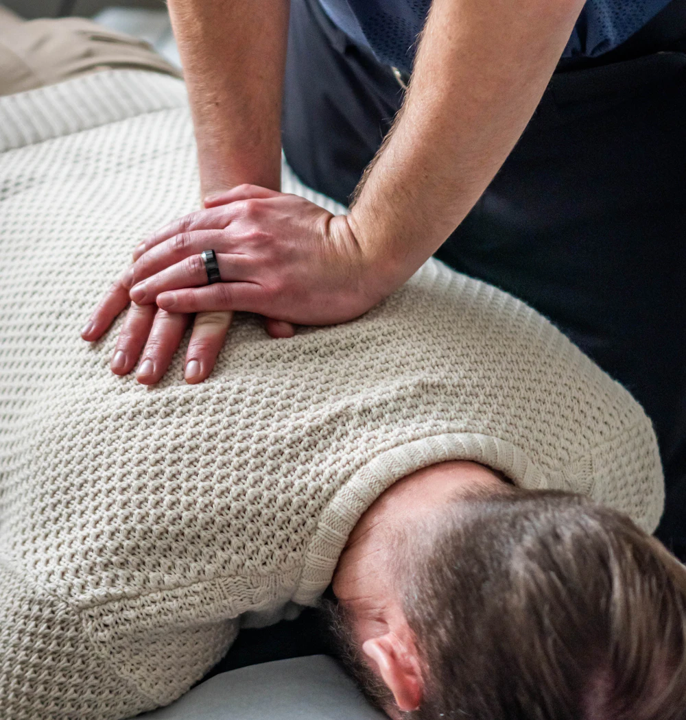 A chiropractor adjusting a patient's upper back